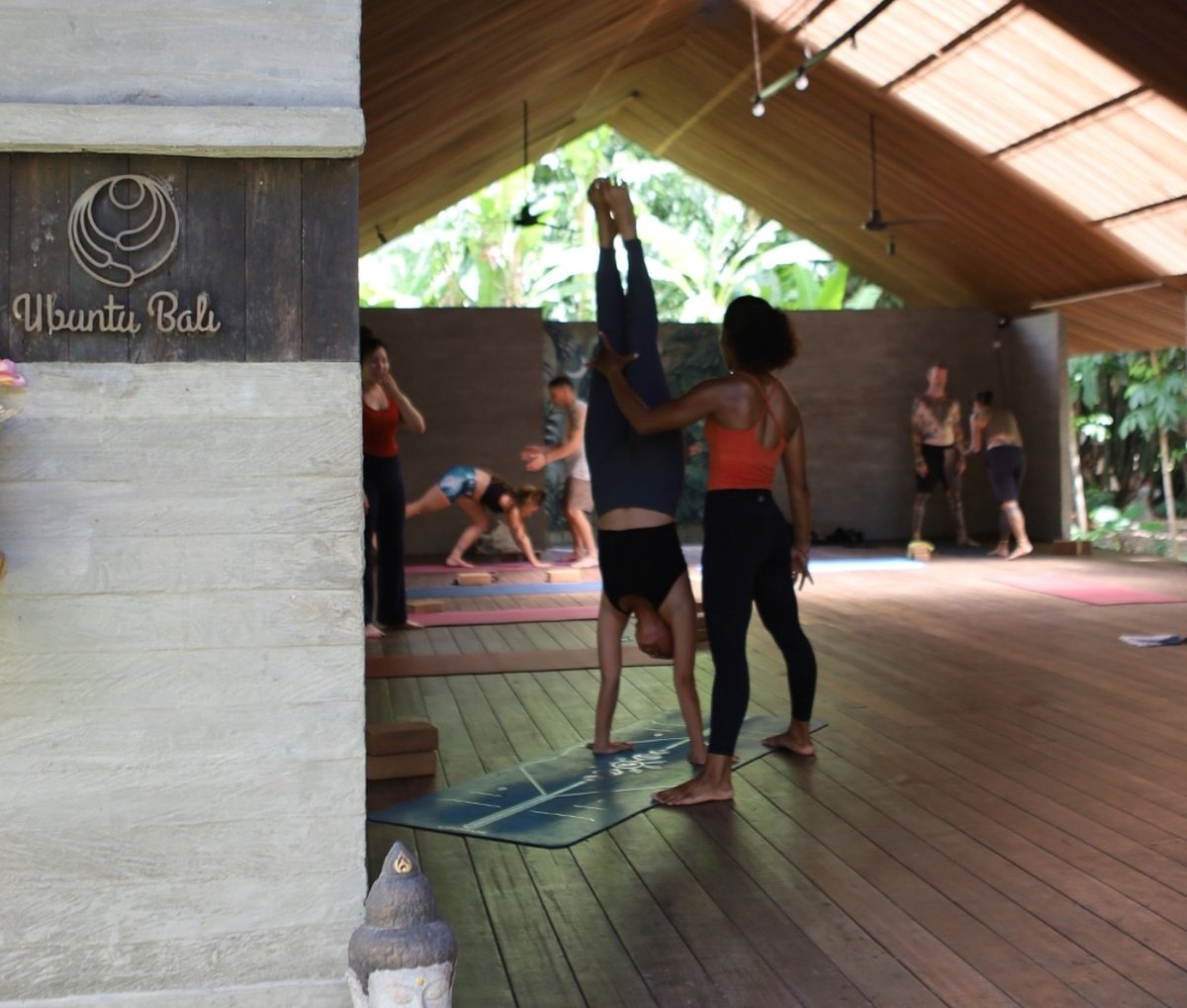 A group yoga class with Indy spotting a handstand at Ubuntu Bali
